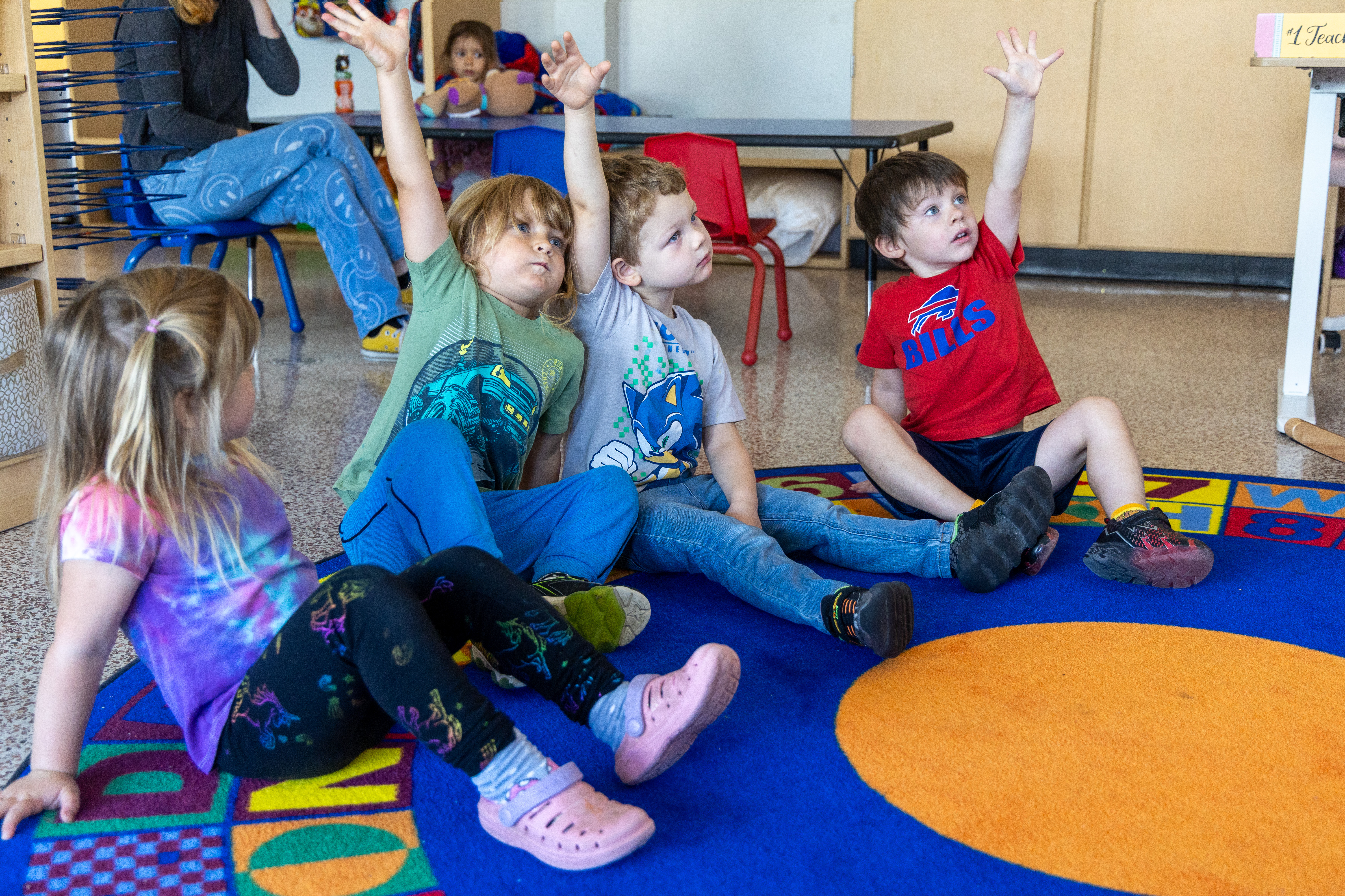 Pre-schoolers raise their hands during a lesson.